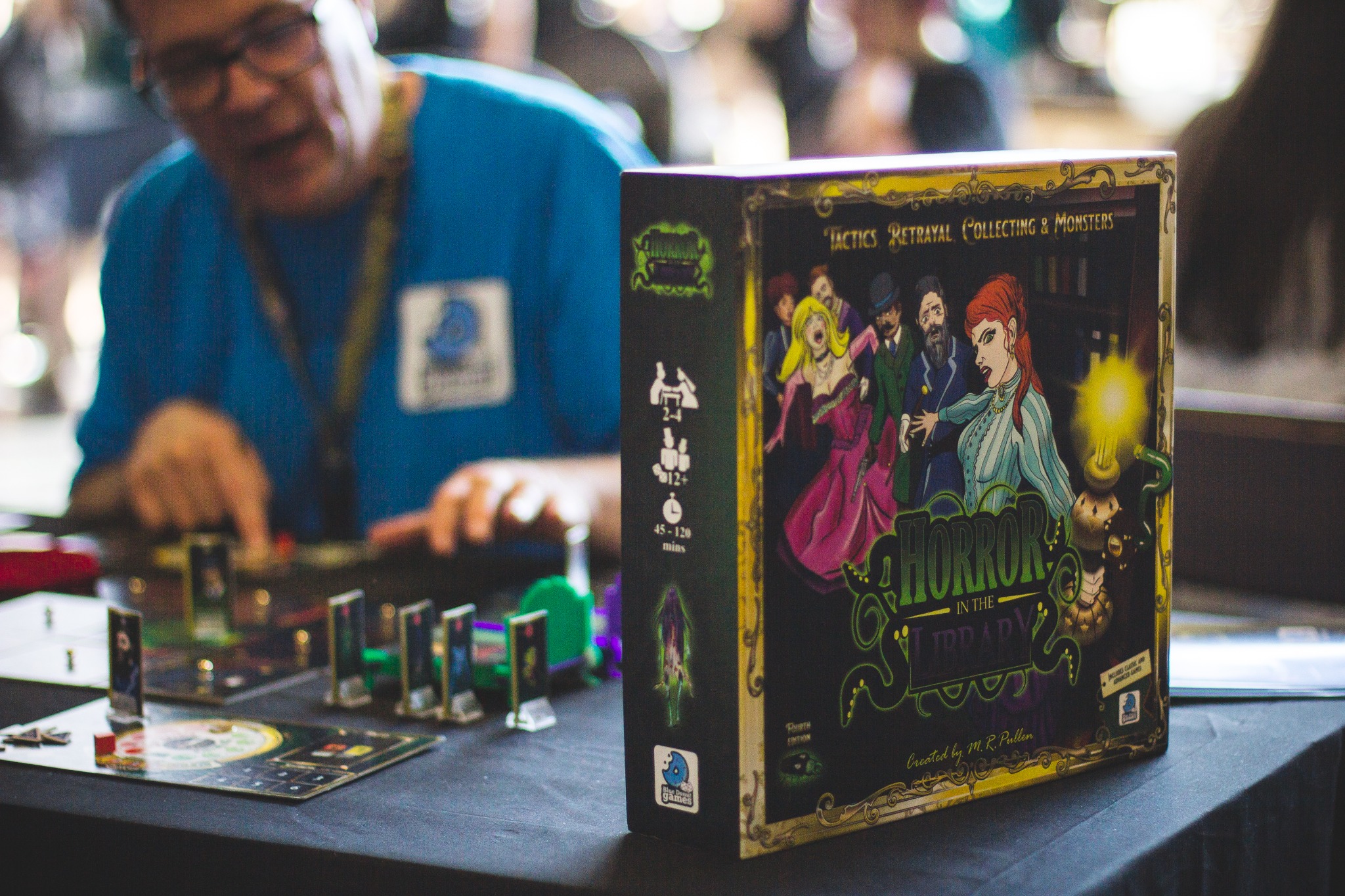 Horror in the Library board game box and components displayed on a table at a live event